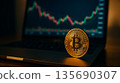 Bitcoin coin standing on laptop keyboard with cryptocurrency trading chart displayed on screen; Bitcoin coin represents finance as Bitcoin links with investment digital currency concept 135690307