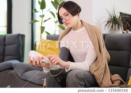 Relaxing at home while monitoring health with a blood pressure cuff and soft blanket in a cozy living space Relaxing at home while monitoring health with a blood pressure cuff and soft blanket in a cozy living space 135690598