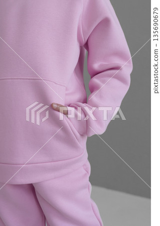 Pink hooded loungewear set with pocket and cuffs. Close-up of warm sportswear sleeve. Pink hooded loungewear set with pocket and cuffs. Close-up of warm sportswear sleeve. 135690679