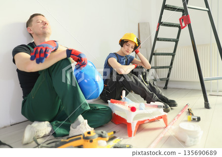 Construction workers take a break during home renovation project in bright indoor setting Construction workers take a break during home renovation project in bright indoor setting 135690689