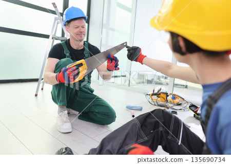 Creative teamwork in a bright, modern workspace as two men collaborate on a hands-on building project with tools 135690734