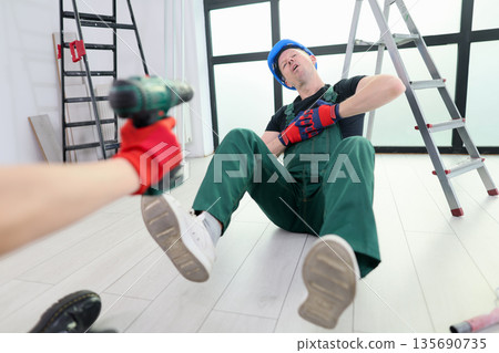 Worker experiences an unfortunate mishap while renovating an indoor space in a modern building setting 135690735