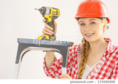 Woman wearing helmet using drill 135690806