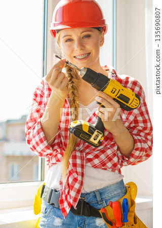 Young woman adjusting her drill doing Young woman adjusting her drill doing 135690807