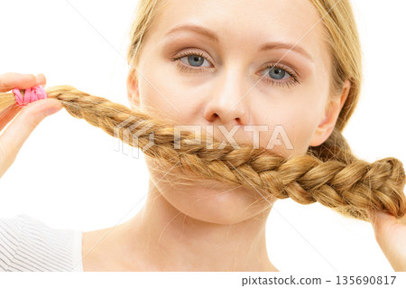 Blonde girl covering her mouth with braid hair Blonde girl covering her mouth with braid hair 135690817