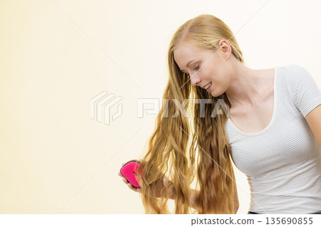 Blonde girl brushing her long hair 135690855