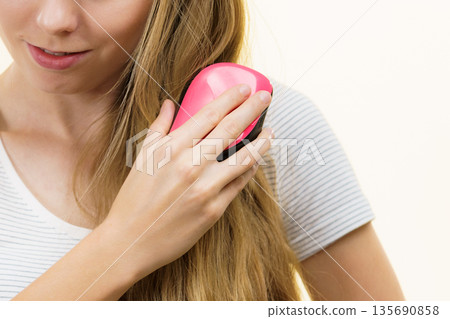Blonde girl brushing her long hair 135690858