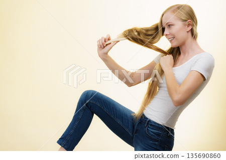 Blonde girl brushing her long hair Blonde girl brushing her long hair 135690860