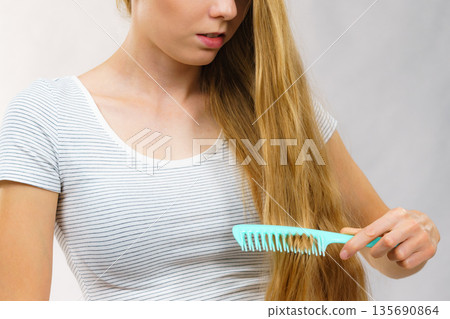 Woman combing long healthy blonde hair Woman combing long healthy blonde hair 135690864