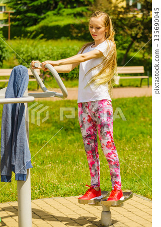 Female doing exercise in outdoor gym 135690945