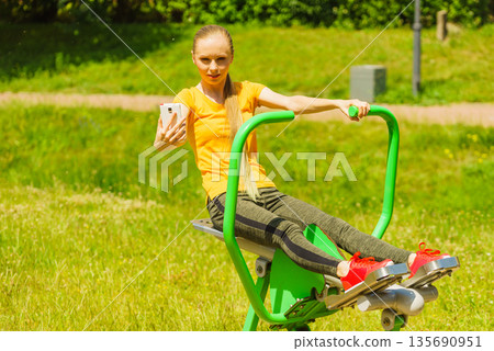 Girl doing exercises outdoor, taking selfie 135690951