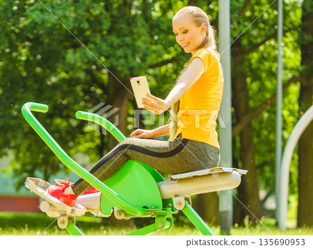Girl doing exercises outdoor, taking selfie 135690953