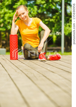 Girl doing exercises outdoor, using roller 135690956