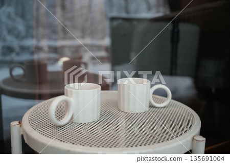 Two White Cups on Outdoor Metal Table Two White Cups on Outdoor Metal Table 135691004