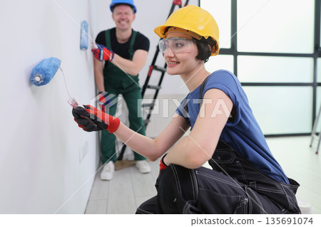 Two cheerful friends painting a room together in vibrant colors during a weekend home makeover adventure Two cheerful friends painting a room together in vibrant colors during a weekend home makeover adventure 135691074