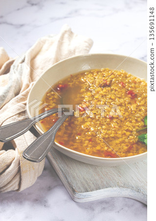 Delicious bowl of flavorful lentil soup with spices and herbs served in a rustic setting Delicious bowl of flavorful lentil soup with spices and herbs served in a rustic setting 135691148