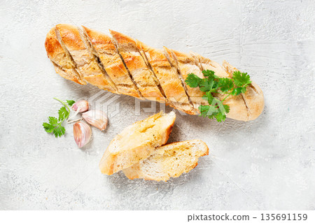 garlic bread,baguette with garlic butter and herbs, on a light table, top view, 135691159