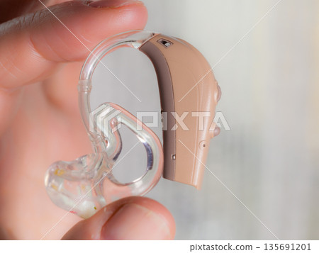 senior person holding hearing aid closeup senior person holding hearing aid closeup 135691201