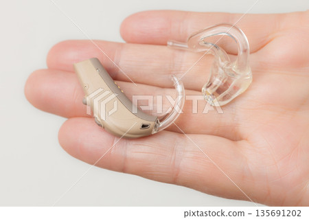 senior person holding hearing aid closeup senior person holding hearing aid closeup 135691202