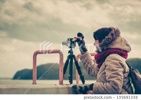 Woman taking pictures on coastline Woman taking pictures on coastline 135691338