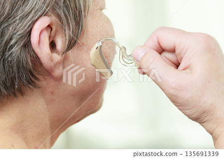 Closeup senior woman using hearing aid 135691339