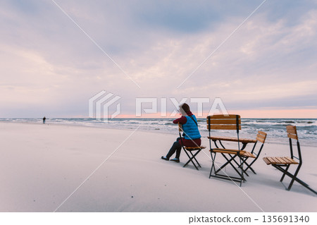 Woman sitting on beach relaxing Woman sitting on beach relaxing 135691340