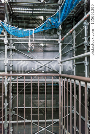 Scaffolding for repairing the exterior walls of an apartment building. Mesh sheet through which the night view can be seen. Construction site background material. Scaffolding for repairing the exterior walls of an apartment building. Mesh sheet through which the night view can be seen. Construction site background material. 135691399