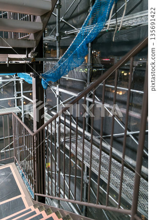 Scaffolding walkway for apartment renovation work, safety net and iron pipes, construction background 135691422
