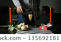 A man pours champagne into glasses as candles roses and gifts decorate the table. St. Valentines day celebration 135692181