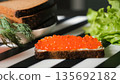 Buttered bread with red caviar on top, with dill and lettuce. Elegant breakfast and premium homemade treat concept  135692182