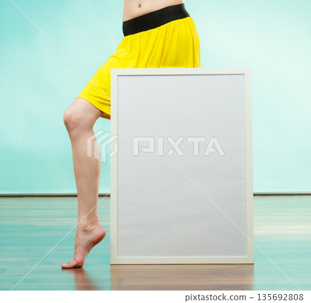 Woman in bikini holds blank presentation board. 135692808