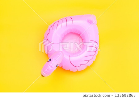 Summer beach composition. Simply minimal design with pink Inflatable flamingo isolated on yellow background. Pool float party, trendy celebrity fashion concept. Flat lay top view copy space 135692863