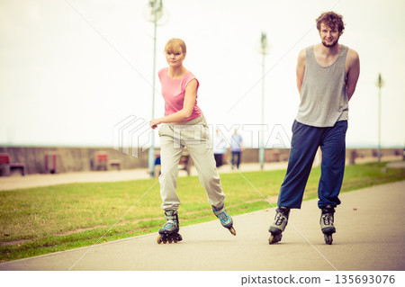Friends rollerblading together have fun in park. 135693076