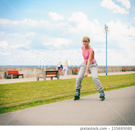 Active young woman rollerskating outdoor. 135693080