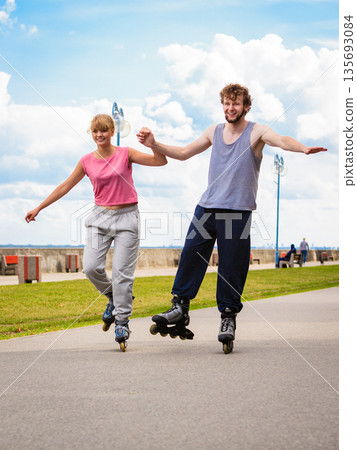 Active young people friends rollerskating outdoor. 135693084