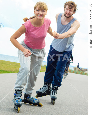 Woman encourage man to do rollerblading Woman encourage man to do rollerblading 135693099