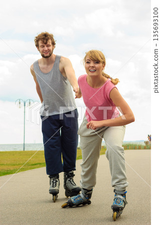 Woman encourage man to do rollerblading 135693100