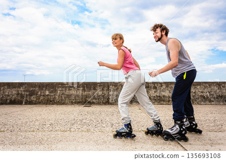 Two people race together riding rollerblades. Two people race together riding rollerblades. 135693108