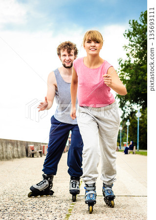 Two people race together riding rollerblades. Two people race together riding rollerblades. 135693111