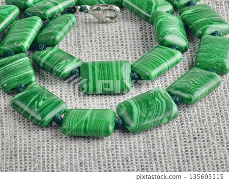 Close-up of green malachite rectangular bead necklace on burlap background Close-up of green malachite rectangular bead necklace on burlap background 135693115
