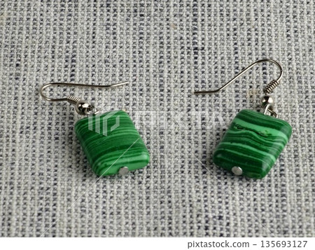 Close-up of green malachite rectangular bead earrings against a burlap background Close-up of green malachite rectangular bead earrings against a burlap background 135693127