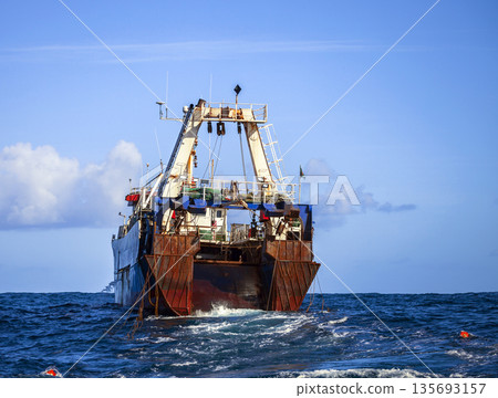 Fishing trawler conducts industrial fishing in the ocean. Fishing trawler conducts industrial fishing in the ocean. 135693157