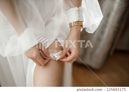 Bride putting on wedding garter before ceremony Bride putting on wedding garter before ceremony 135693175