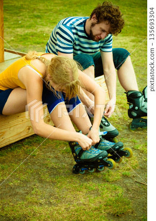 Woman and man putting on roller skates Woman and man putting on roller skates 135693304