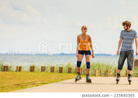 Young couple on roller skates riding outdoors 135693305