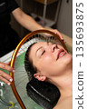 Luxury wellness experience featuring a woman during a calming scalp and hair treatment with water flow. 135693875