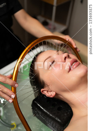 Luxury wellness experience featuring a woman during a calming scalp and hair treatment with water flow. Luxury wellness experience featuring a woman during a calming scalp and hair treatment with water flow. 135693875