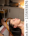 Luxury wellness experience featuring a woman during a calming scalp and hair treatment with water flow. 135693876