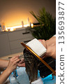 Woman receiving a relaxing head spa treatment with flowing water and professional scalp massage in a wellness salon. 135693877