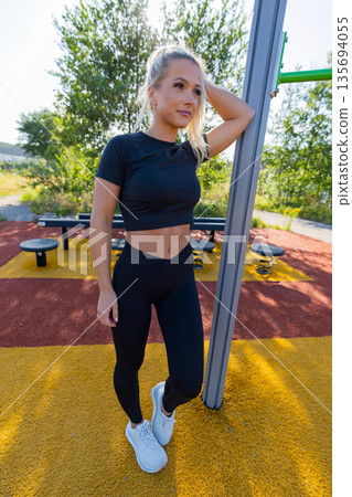 Young woman resting during outdoor fitness workout at park in athletic outfit Young woman resting during outdoor fitness workout at park in athletic outfit 135694055